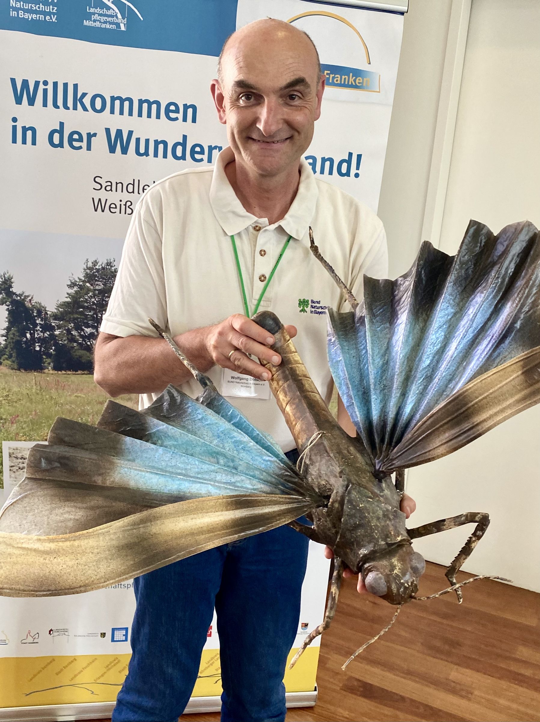 Wolfgang Dötsch mit Modell der Blauflügeligen Ödlandschrecke